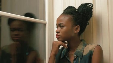 Trendy-moody Afro-Amerikan kadın giyinmiş Afrika pigtails pencere ve ileri ile bakan ile yakın çekim yan portresi