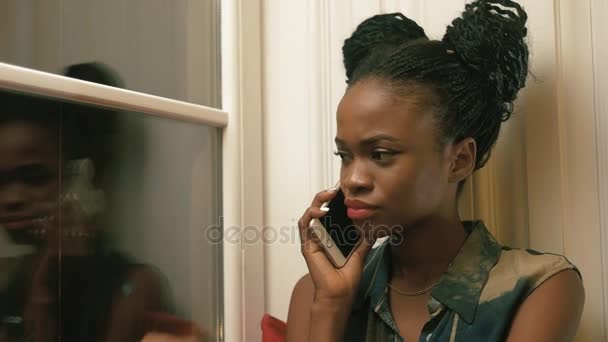 Retrato de close-up. Rapariga afro-americana perturbada com tranças africanas a falar ao telefone com a amiga. A reação nas notícias — Vídeo de Stock