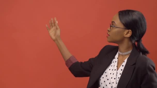 Mujer negra habla sobre el tema de pie ante la pared roja — Vídeo de stock