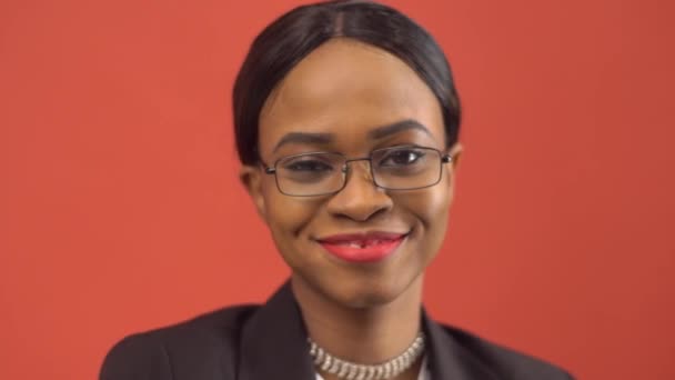 Black woman winks at someone standing before red wall — Stock Video