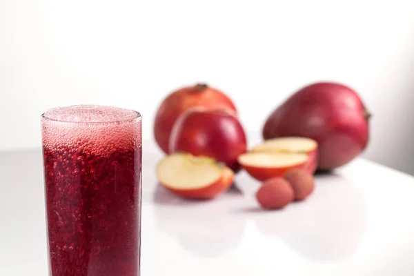 Copo cheio de suco de cereja ou romã com bolhas. Frutas e fundo branco — Fotografia de Stock