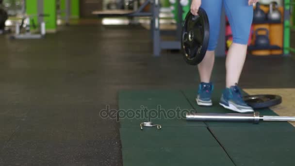 La foto horizontal de la chica con tatuaje en pantalones azules preparándose para hacer ejercicios con la barra — Vídeos de Stock