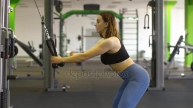 Kadın kol kasları zinde ve pompa tutmak için yeşil spor salonunda eğitim siyah üst ve Mavi pantolon