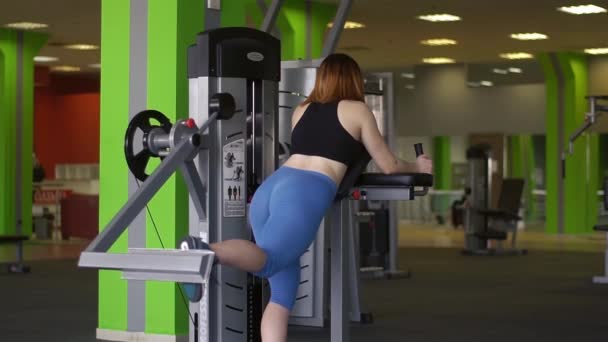 Das Rückenporträt der Sportlerin, die Übungen auf dem Trainer macht, um ihren Körper zu entwickeln, um fit zu bleiben. — Stockvideo