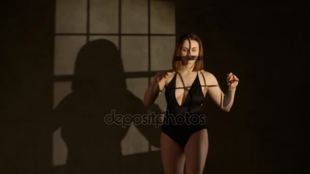 Портрет женщины с короткими светлыми волосами в черном закрытом халате на фоне черной стены — стоковое видео