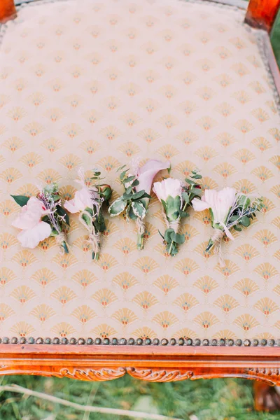 Os encantadores mini-buquês de flores rosa claras estão deitados na cadeira moderna localizada na grama verde. Linda composição . — Fotografia de Stock