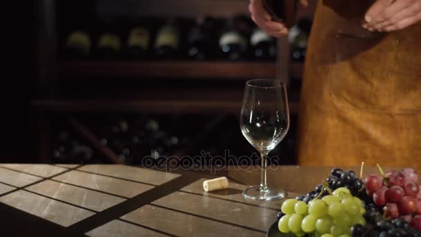 De sommelier is langzaam het invullen van het glas met witte wijn. De prachtige samenstelling van de kleurrijke sappige druiven geplaatst op de zwarte plaat en de schaduwen van het venster. — Stockvideo