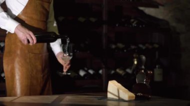 Sommelier şarap deposu beyaz şarap ile cam fillinf var. Lezzetli peynir masanın üzerine yerleştirilir.