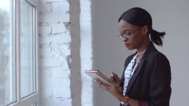 Kvinnan läser något i sin ipad stående i vita rummet — Stockvideo