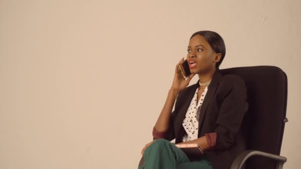 Oldukça siyah Bayan görüşmeler office sandalyede otururken telefonda — Stok video