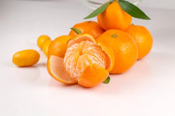 Gepelde rijpe tangerine tegenover andere mandarijnen op een witte ondergrond — Stockfoto