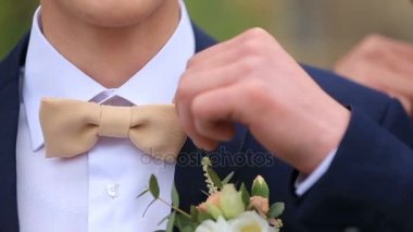 Mavi elbiseli adamlar bej papyon boyunlarına üzerinde düzeltmek.