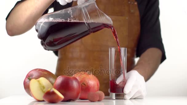 Mann gießt Saft in Glas auf Tisch mit Früchten — Stockvideo