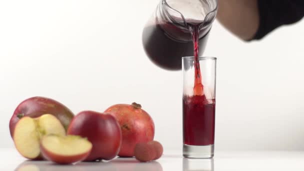 Επανδρώνει χέρι χύνει χυμό σε ένα ποτήρι στο τραπέζι με κόκκινα φρούτα — Αρχείο Βίντεο
