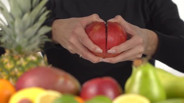 Vrouw opent granaatappel boven de tafel met exotische vruchten — Stockvideo