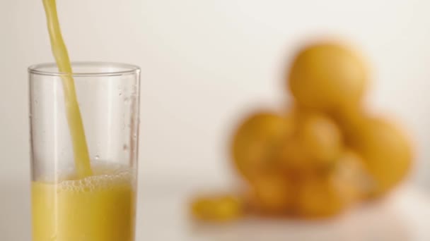 Сок наливается в стекло на стол с апельсинами и мандаринами — стоковое видео