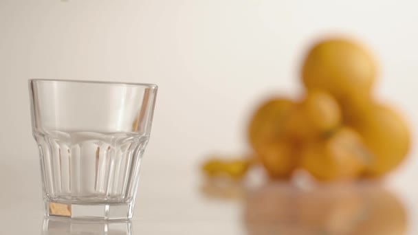 El jugo de naranja vierte en un vaso sobre la mesa con naranjas y mandarinas — Vídeo de stock