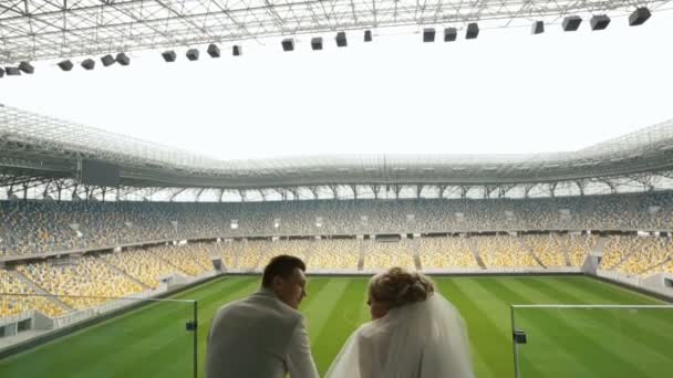 Bride and groom talk looking at football field — Stock Video