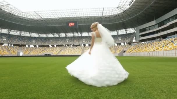 Blonde bride whirls on football field — Stock Video