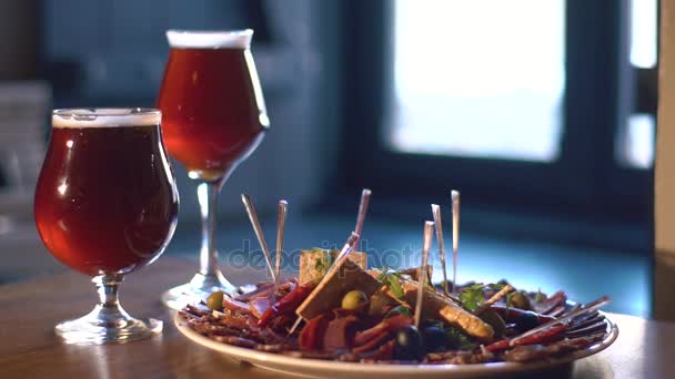 La composición del plato de carne colocado junto a dos vasos con cerveza detrás de la ventana . — Vídeo de stock