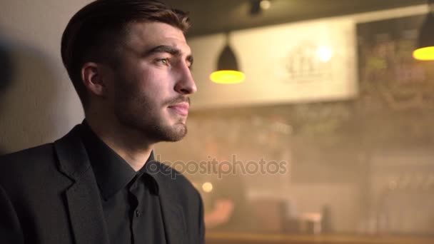 Het portret van de close-up kant van de streek mab in het zwarte pak drinken bier en kijken ergens anders in de bar. — Stockvideo