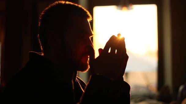 El retrato lateral de cerca del hombre molesto manteniendo sus manos en el signo para rezar al fondo de la puesta del sol . — Vídeo de stock