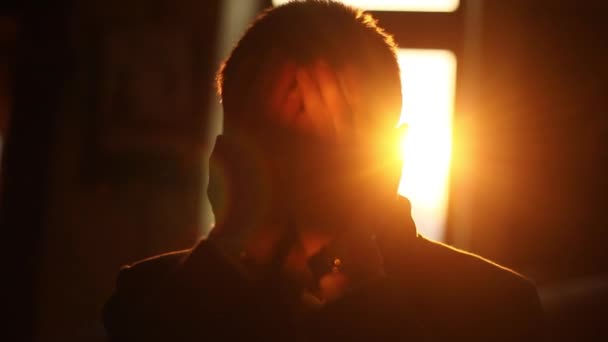 De close-up voorkant portret van de depressieve man zijn gezicht met de handen te sluiten. De zonsondergang. — Stockvideo