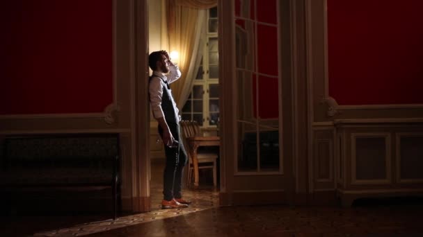La composizione dell'uomo depresso che tiene il bicchiere da vino, versando vino bianco fuori, appoggiato al muro nella sala dal design aristocratico . — Video Stock