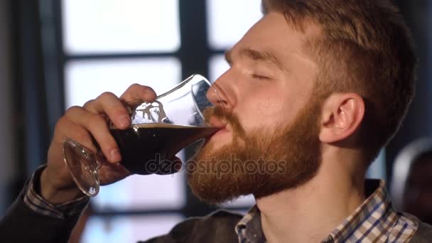 Das Nahaufnahme-Porträt des Mannes mit Bart, der in der örtlichen Bar sein Bier trinkt und genießt. — Stockvideo