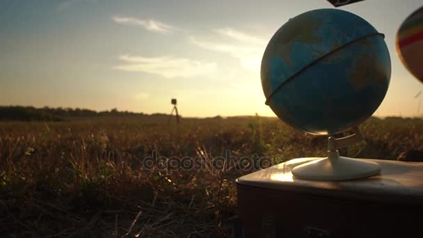 Die Nahkomposition der Erdkugel, die während des Sonnenuntergangs auf dem alten Koffer im Feld platziert wurde. — Stockvideo