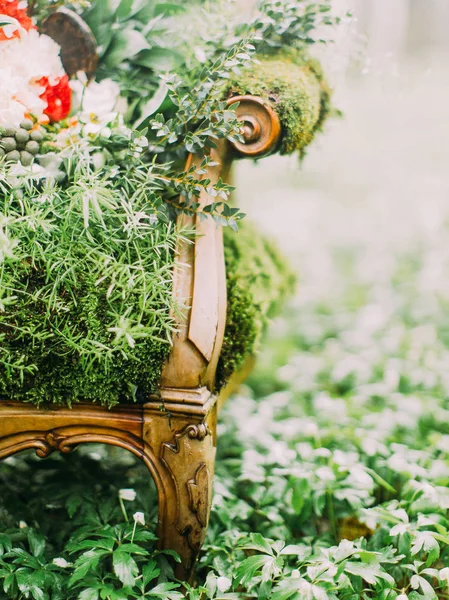 The part of the old moss overgrown chair and the colourful bouquet placed on it. The green forest composition. — Stock Photo, Image