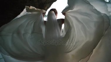 Uzun beyaz düğün elbisesini yeşil alanında yer alan kayalar ile oynayan sarışın gelin yakın çekim portresi.
