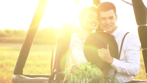 The close-up portrait of the lovely happy vintage dressed couple holding the black hat and standing in the airballoon. The sunset composition. — Stock Video