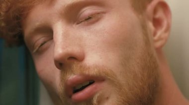 Yüzü yorgun ve hasta altın kıvırcık saçlı adam ve öksürük sakal. Yakın çekim portre