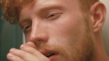 Yakın çekim portre. Altın kıvırcık saç ve sakal ile yorgun, hasta ve neredeyse uyudu adamın yüzü. O öksürük