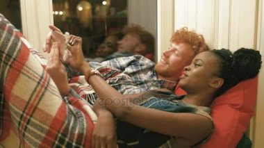 Altın saçlı ve sakallı ve selfies cep telefonu üzerinden alarak kırmızı örgü şal içinde sarılı gülümseyen Afro-Amerikan kadın, mutlu bir adam portresi. Kaşlarını taşınıyor