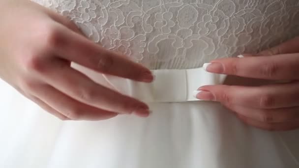 Les mains douces de la mariée corrigent l'arc sur la robe de mariée blanche . — Video