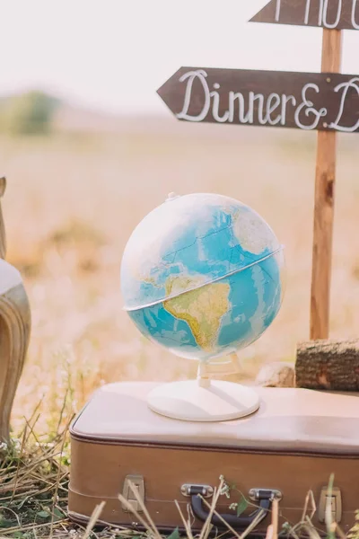 Крупним планом фотографія земної кулі, розміщена на валізі на тлі дерев'яних бляшок зі знаком Вечеря на сонячному полі . — стокове фото