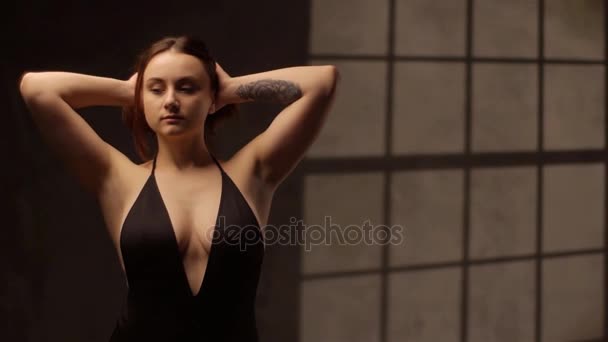 Das Nahaufnahme-Porträt der schönen Frau mit der Tätowierung am Arm im schwarzen Badeanzug, die mit ihren Haaren spielt. — Stockvideo