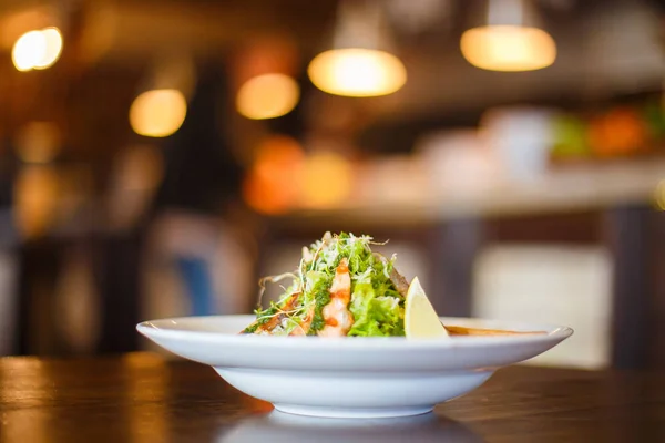 Het portret van de kant van de salade in de vorm van de piramide bestond uit de Gegrilde forel, sla, citroen en versierd met Parmezaanse kaas op de onscherpe achtergrond van het restaurant. — Stockfoto