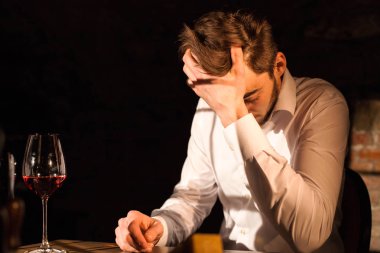 Onun eğilerek masaya oturan yakışıklı adam eline haed. Adamın yanına yerleştirilen şarap.