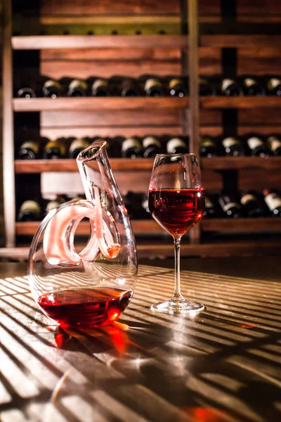 Bright shot of wine glass and carafe filled with red wine placed on the table. — Stock Photo, Image