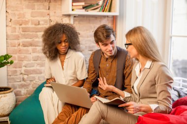 Birisi oturuyor ve bir şey tartışırken Afro-Amerikan kız olmak üzere üç genç insanlar. Bir dizüstü bilgisayar tutan çocuk.