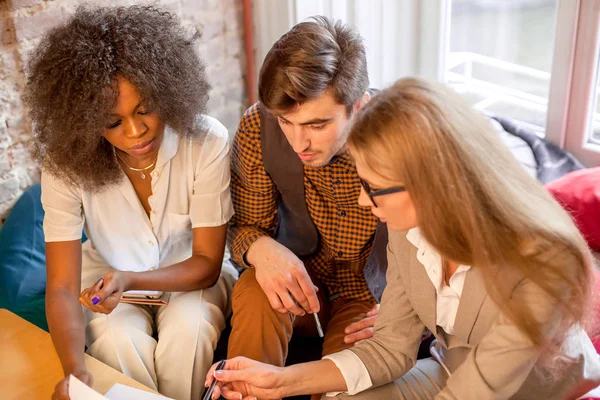 Jóvenes en ropa de trabajo conversando en su oficina . — Foto de Stock