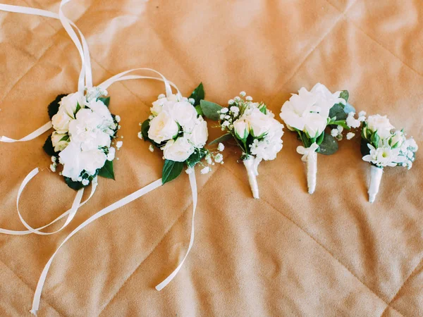 La vista anterior de la boda mini-ramos y brazalete de flores envueltos en cintas blancas colocadas en la cama . — Foto de Stock