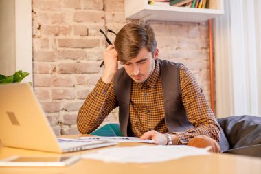 Güzel ofisinde oturan ve bir dizüstü bilgisayar üzerinde çalışan yakışıklı adam.