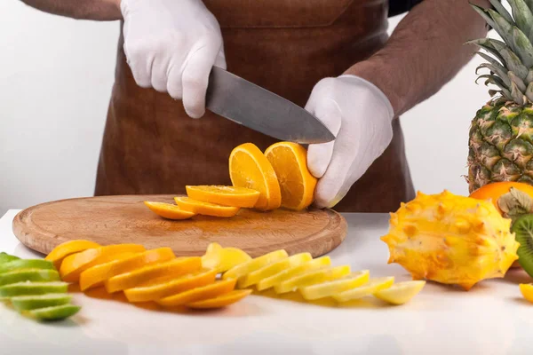 Chef cortar una fruta en una tabla de cortar de madera. Composición de frutas — Foto de Stock