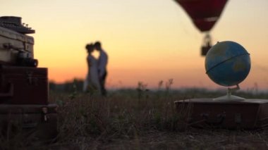 Romantik Çift kalma. Sunset bulvarında eski bavulları ön plan, arka plan ve küre modeliyle, kadar uçan balon ile öpüşme bulanık hipster Çift