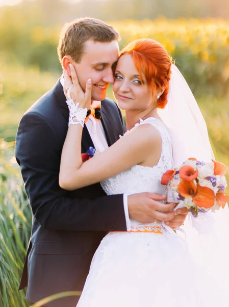 Novia pelirroja y elegante novio guapo posando en un campo soleado girasol. Concepto de boda —  Fotos de Stock