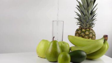 Yeşil kompozisyon muz, elma, ananas ve armut oluşuyordu. Yüksek cam su ile doldurma.